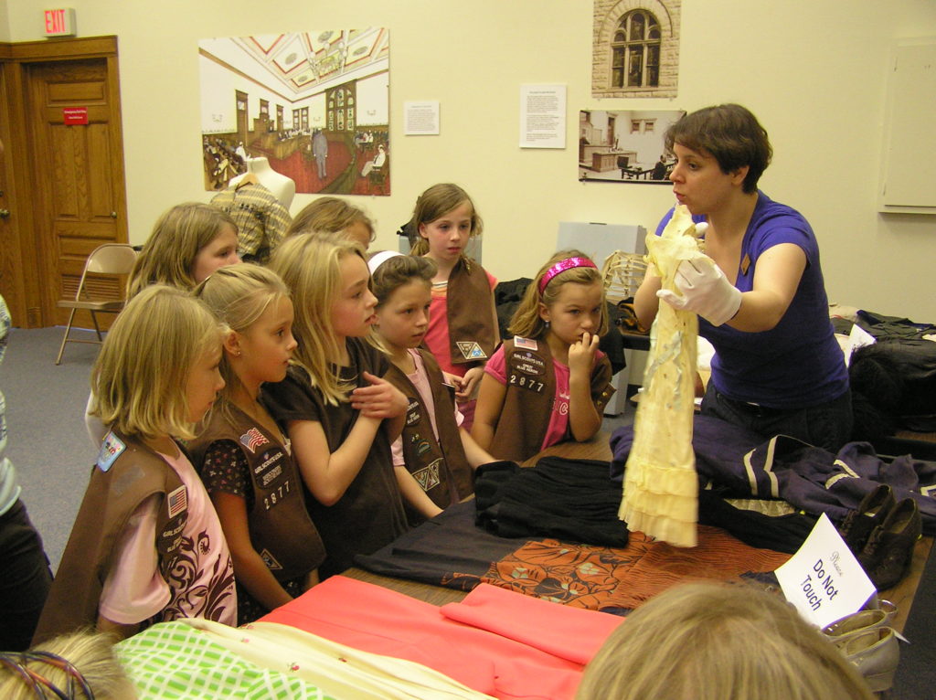 A group of girl scouts learning about old fashioned clothing